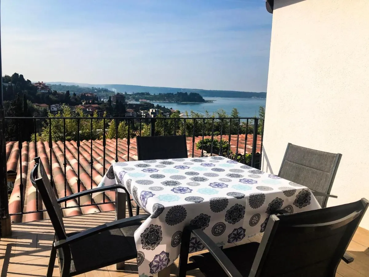 Miza na balkonu Apartmaja 3, spodaj strehe Portoroža in zaliv